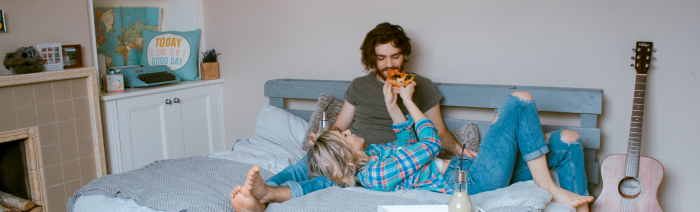 urlaub zuhause: Bild von Paar in Bett beim Pizza Essen