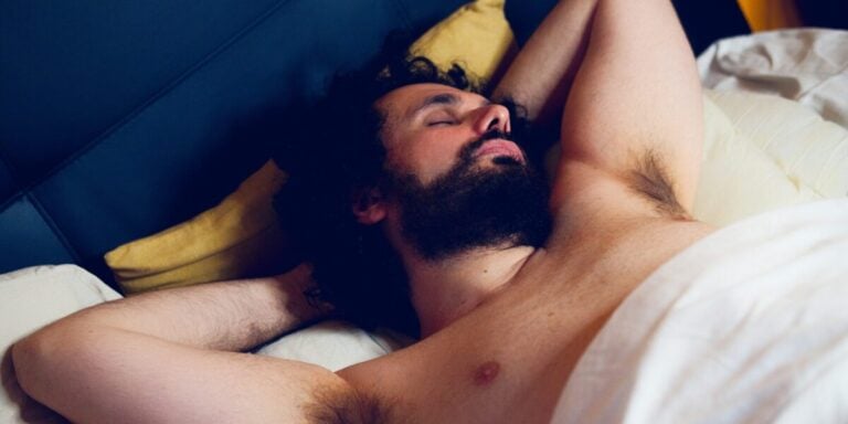 Bärtiger Mann liebt mit nacktem Oberkörper im Bett