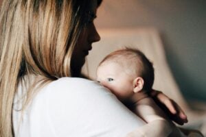 Postpartale Depression: Mutter mit Gesicht im Schatten trägt ein Baby