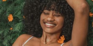 Sexuelle Gesundheit: schwarze Frau liegt lächelnd auf Bumenwiese