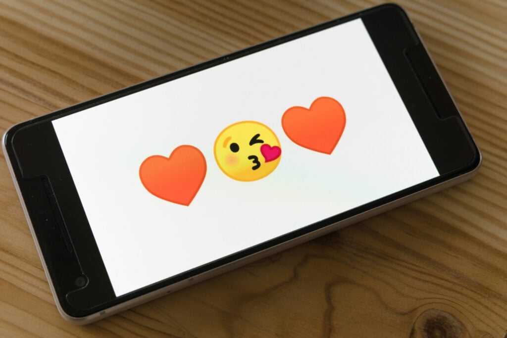 Online-Dating: Handy-Screen mit Herz und Kuss-Emoji