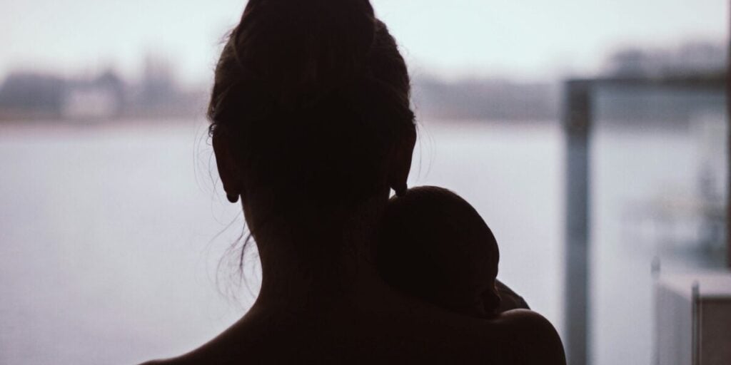 Postpartale Depression: Mutter mit Baby im Gegenlicht