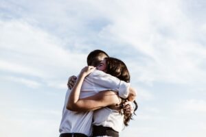Coming-Out: Zwei Menschen umarmen sich unter freiem Himmel